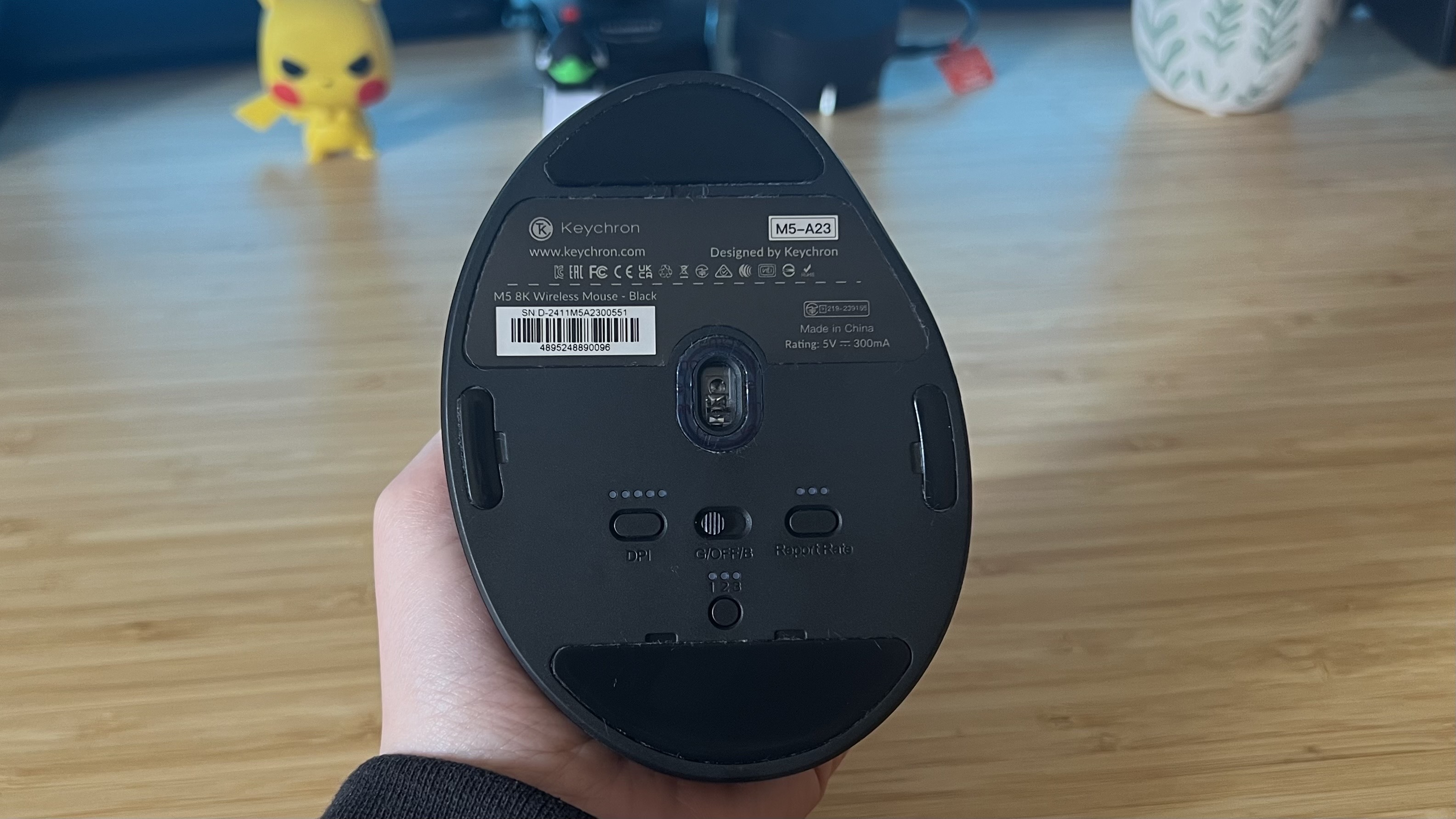 Underside of Keychron M5 gaming mouse showing DPI and report rate settings, power button, and sensor