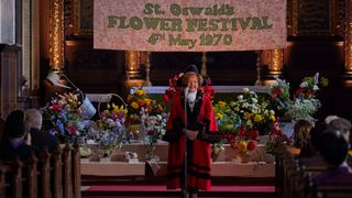 Violet in her red mayor robes standing at the front of the church, opening the flower festival in Call the Midwife season 14 ep 2