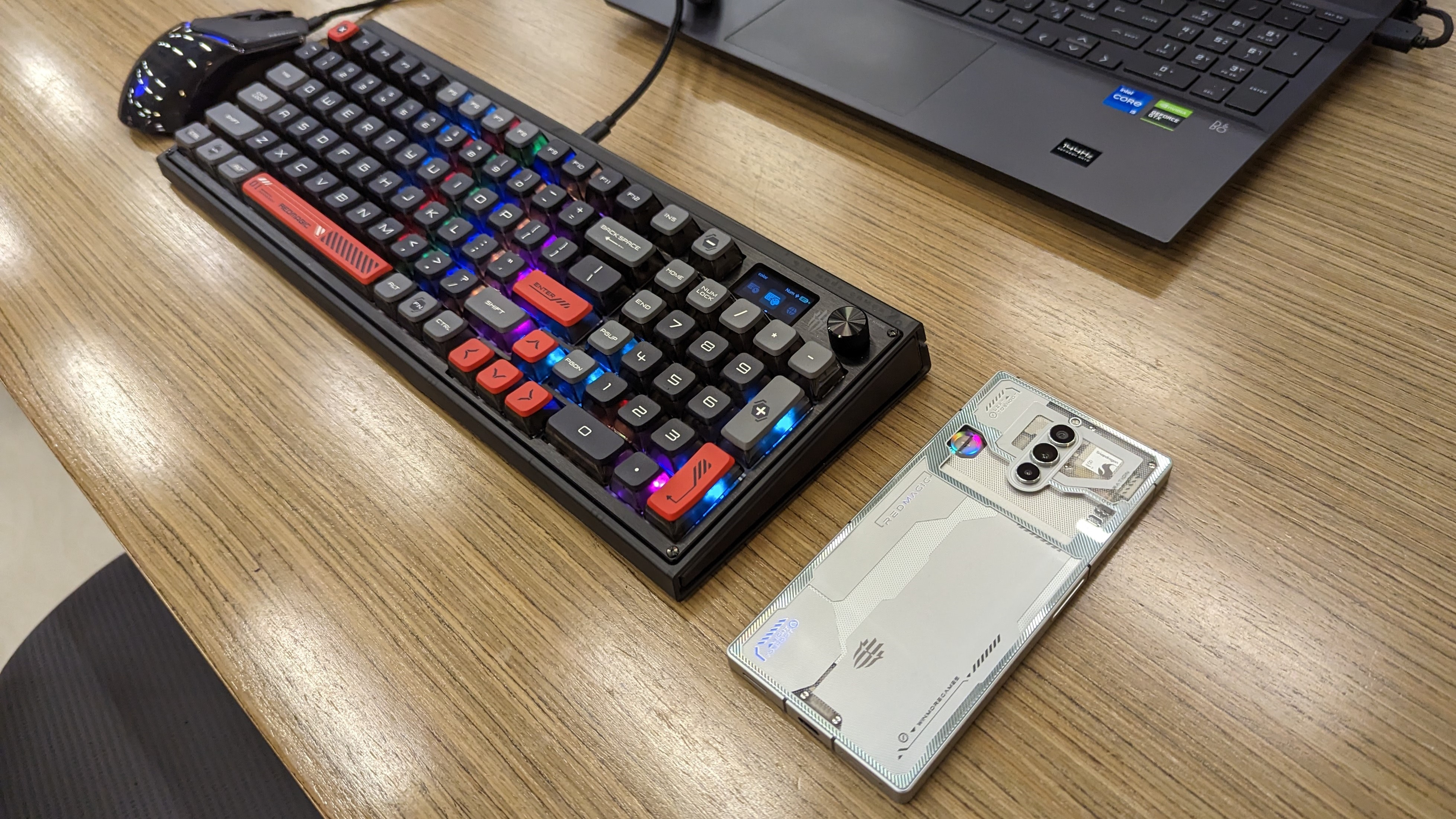 RedMagic 8 Pro وماوس ولوحة مفاتيح ميكانيكية على مكتب خشبي.