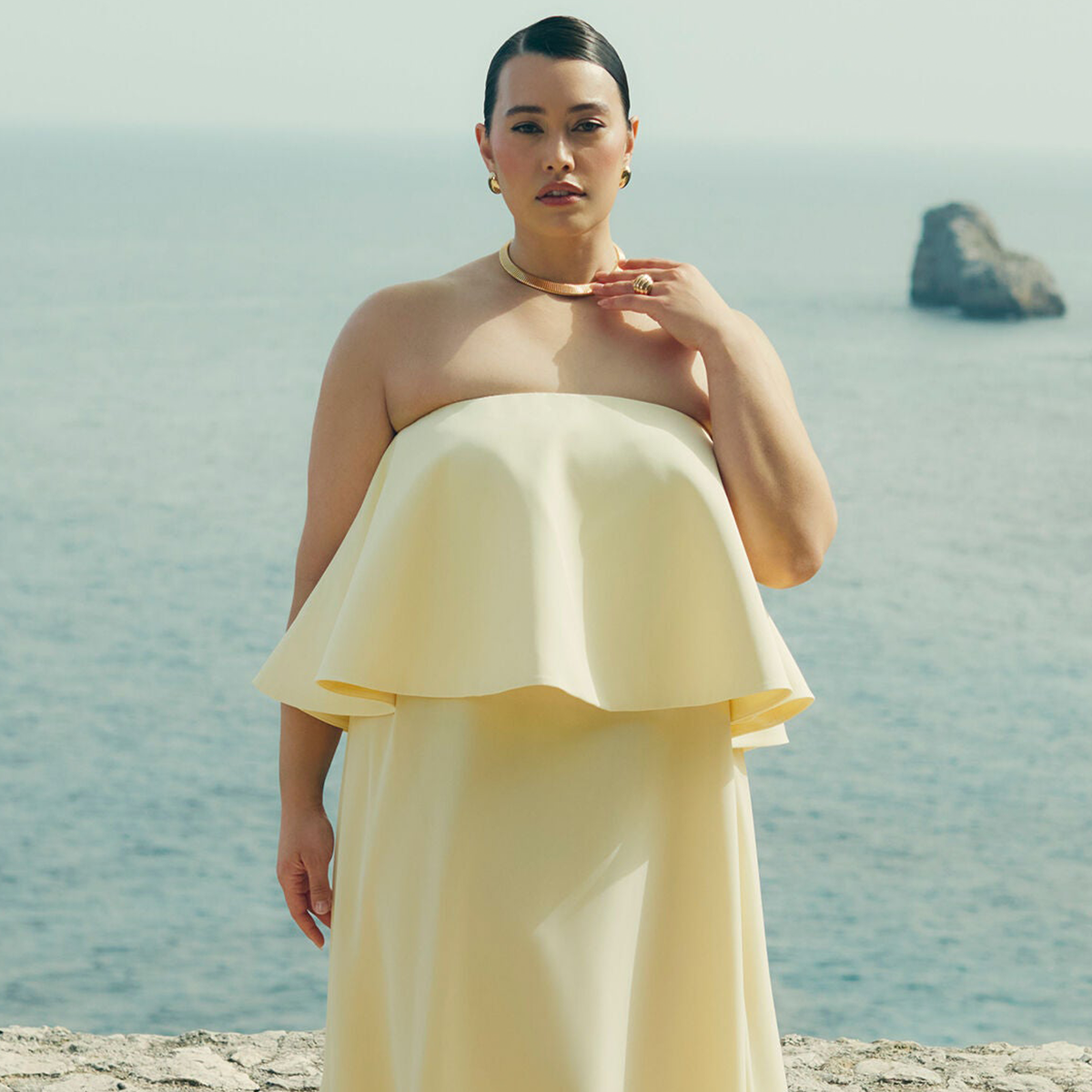 Model wears yellow plus-size wedding guest dress from Eloquii
