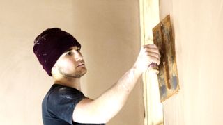 Man plastering interior wall