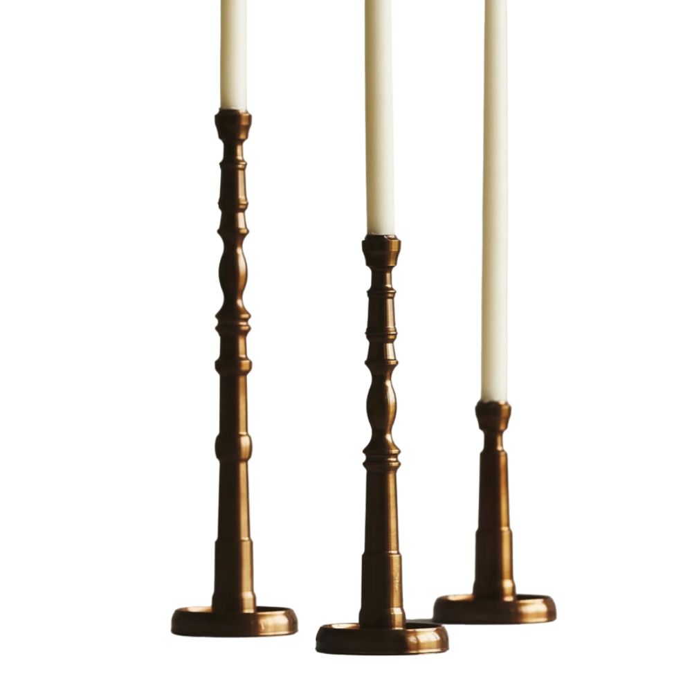 three brass candlesticks with white taper candles in