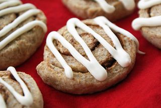 close up of a cinnamon bun bite with white icing drizzled over the top on a red tablecloth