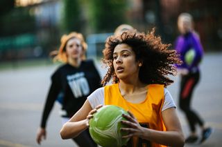 Goal setting: action shot of netball player catching ball on outdoor sports court