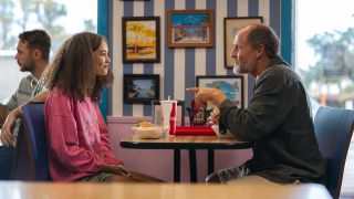 Nico Parker and Woody Harrelson facing each other in a diner in Suncoast