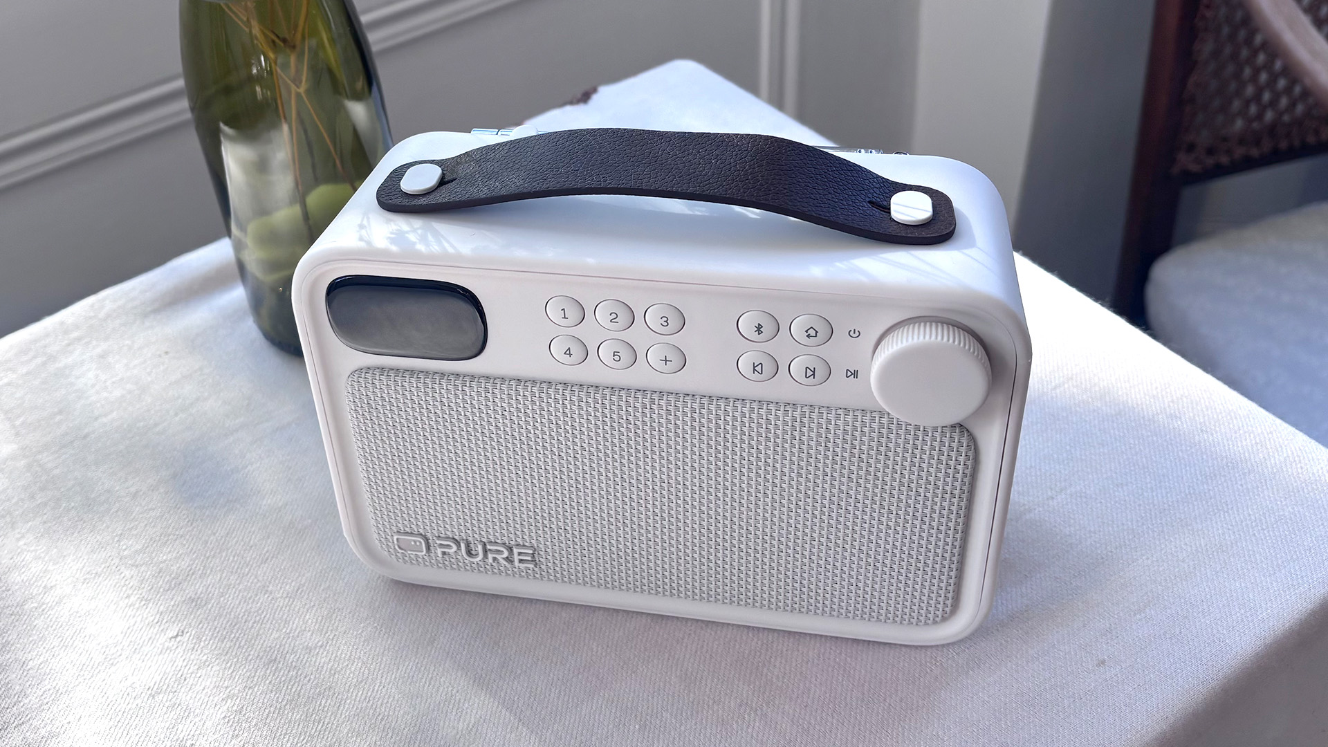 Pure Bloom DAB radio on white table cloth next to green bottle