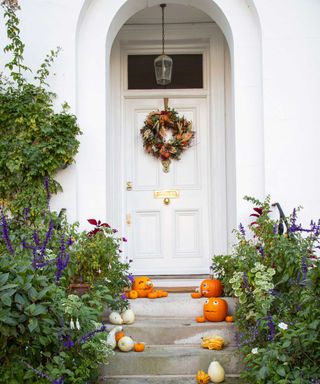 halloween wreath and pumpkins on elegant front door, set up by Maison de Fleurs