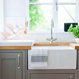 A kitchen sink with a window behind it and a dish drying rack next to it