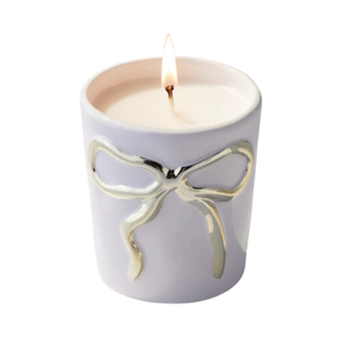 Bow candle holder in bedroom setting with perfurmes in background