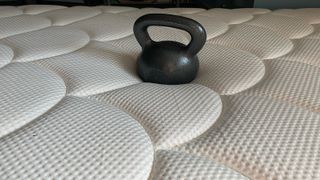 DreamCloud Mattress with a kettlebell in the middle to test pressure relief