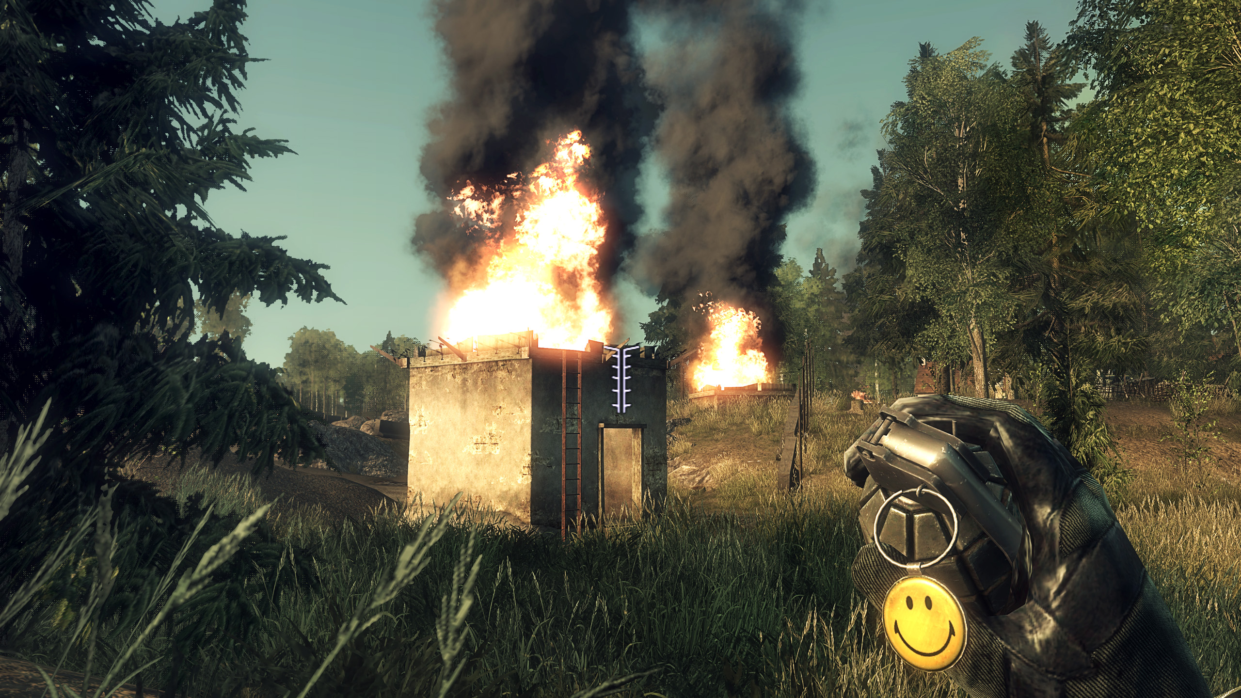 Battlefield Bad Company picture showing someone holding a grenade with a smiley face tag in front of a burning concrete shack