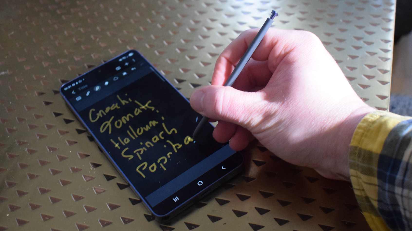 The Samsung Galaxy S26 Ultra on a table, with a manusing the stylus to write a shopping list.