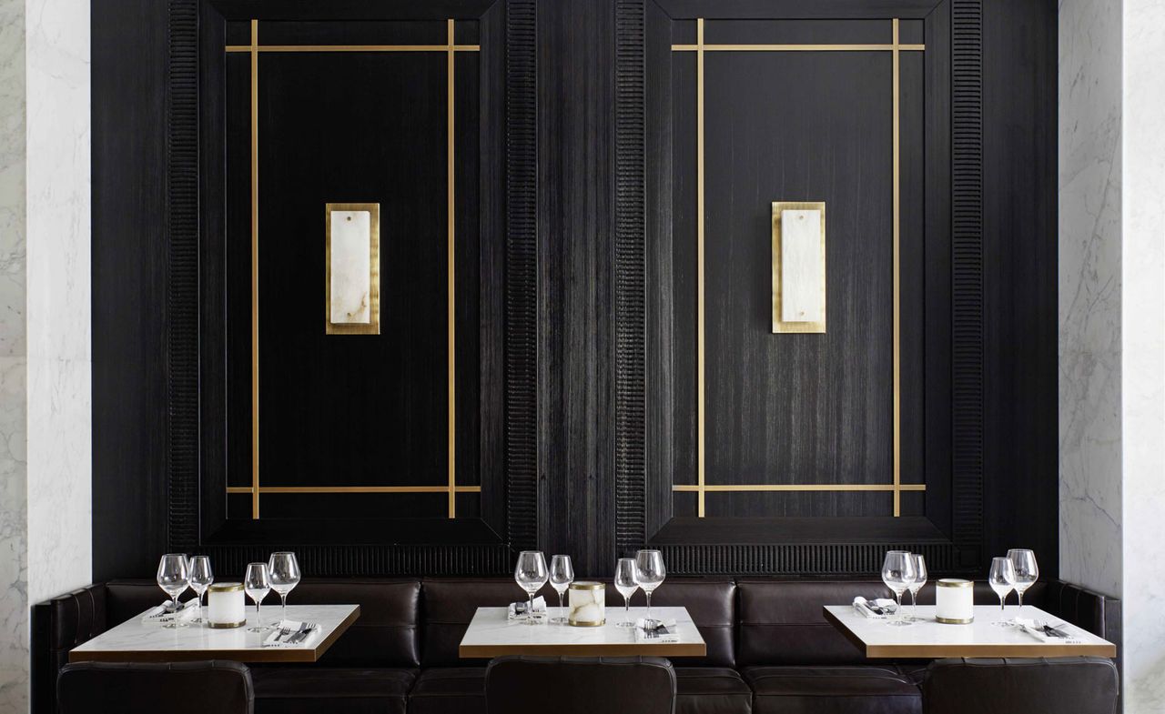 Dark wooden wall paneling, brown leather couches with single square tables 