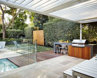 A backyard terrace with decked pool and bbq area