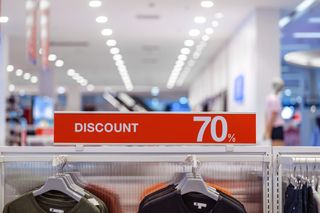 Discount 70% label of sales tag price over the clothes line in the store for shopping.