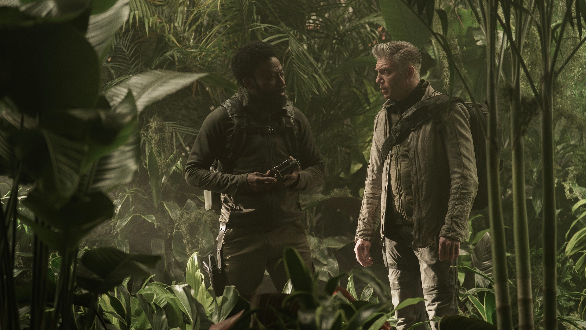 Two men are exploring a jungle. L to R Babs Olusanmokun as Dr. MíBenga and Anson Mount as Capt. Pike in season 3 , Episode 3 of Strange New Worlds streaming on Paramount+.