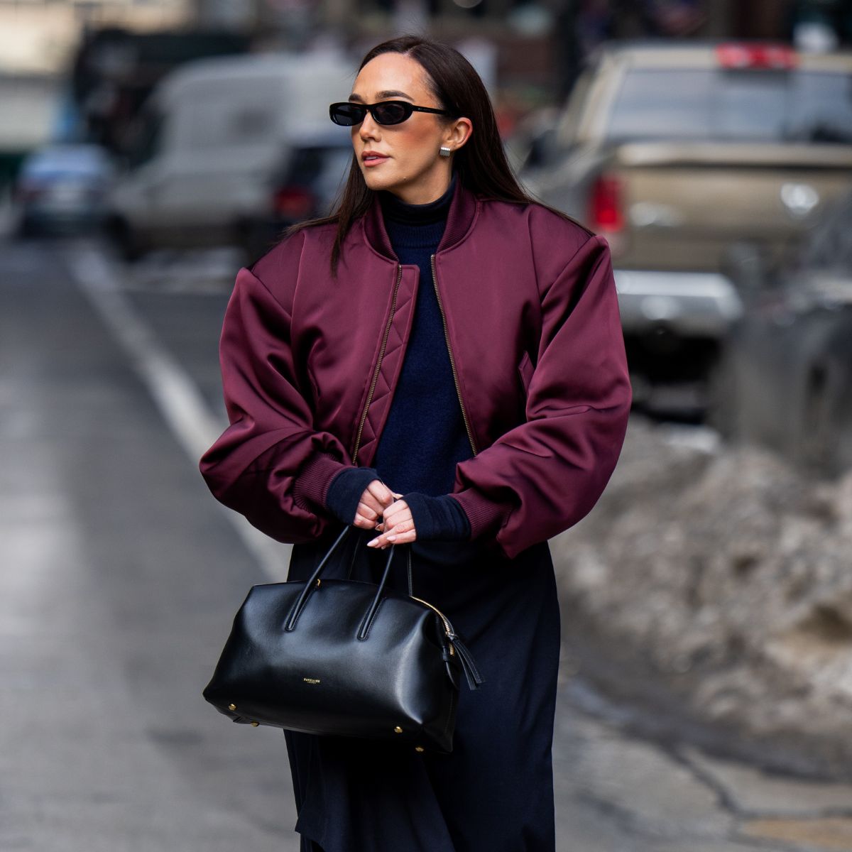 a street style photo of a woman wearing a demellier stockholm bag and a satin bomber jacket