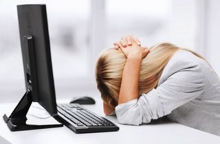A woman sits at her computer, looking very stressed.