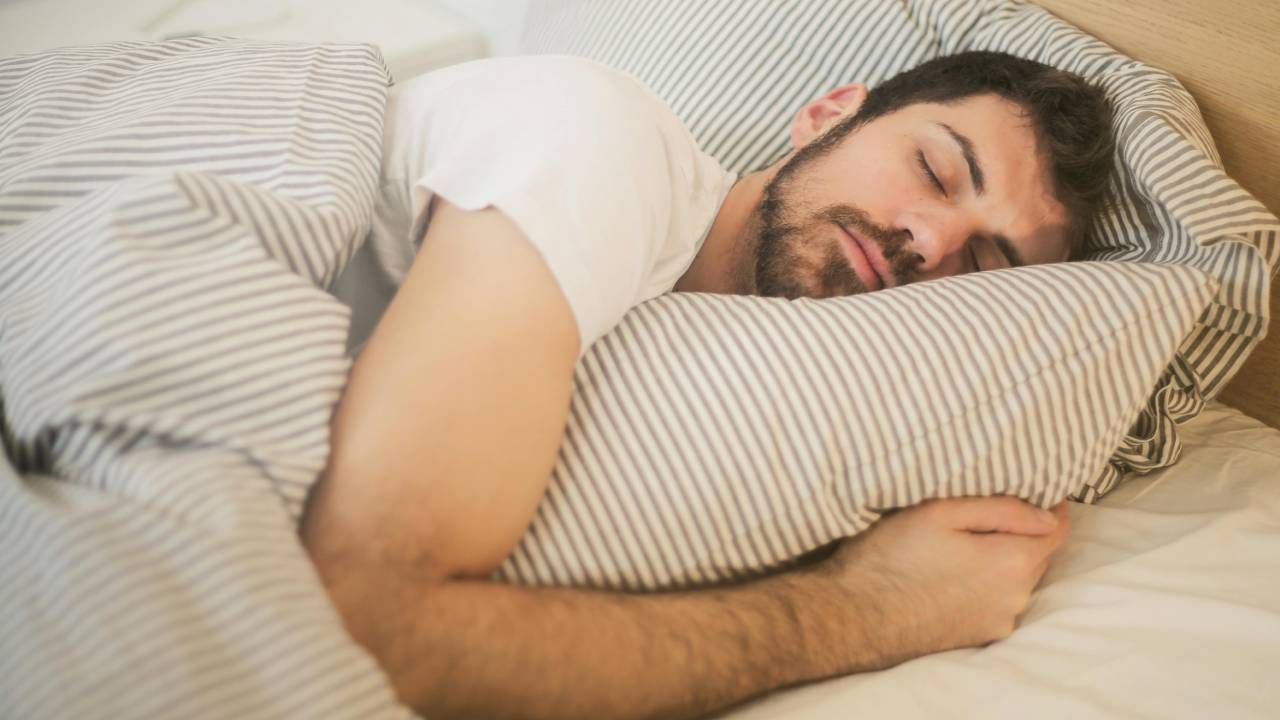 A man sleeping in bed with a stripy duvet