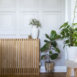 Hallway with wooden slatted cabinet and fake panelled wallpaper in grey.