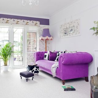 living room with purple sofa and white walls