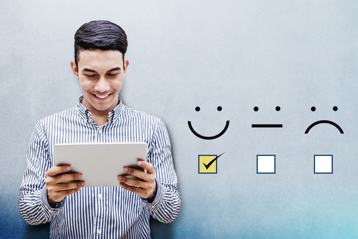 A man looks at his tablet with a happy expression