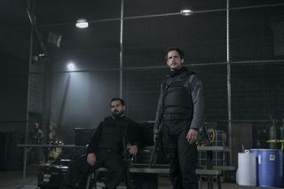 Michael Malarkey as Markus and Rob Heaps as Tomas Bala sitting in a warehouse in a still from the night agent season 2