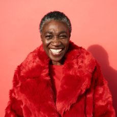 best foundation for mature skin - mature woman smiling wearing a red faux fur coat - gettyimages 901579350 