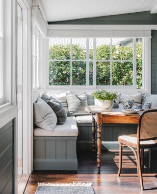 dining room with built in gray bench, gray and neutral cushions and vintage wooden table and chairs
