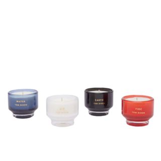 four scented candles in green, white, black and red glass vessels