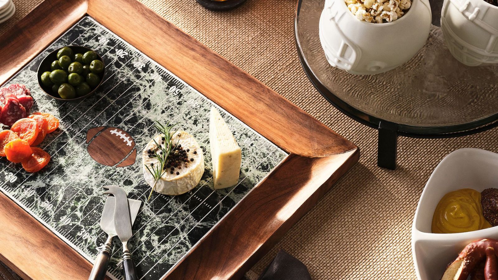 Football-themed cheeseboard next to stone football helmet-shaped snack bowls
