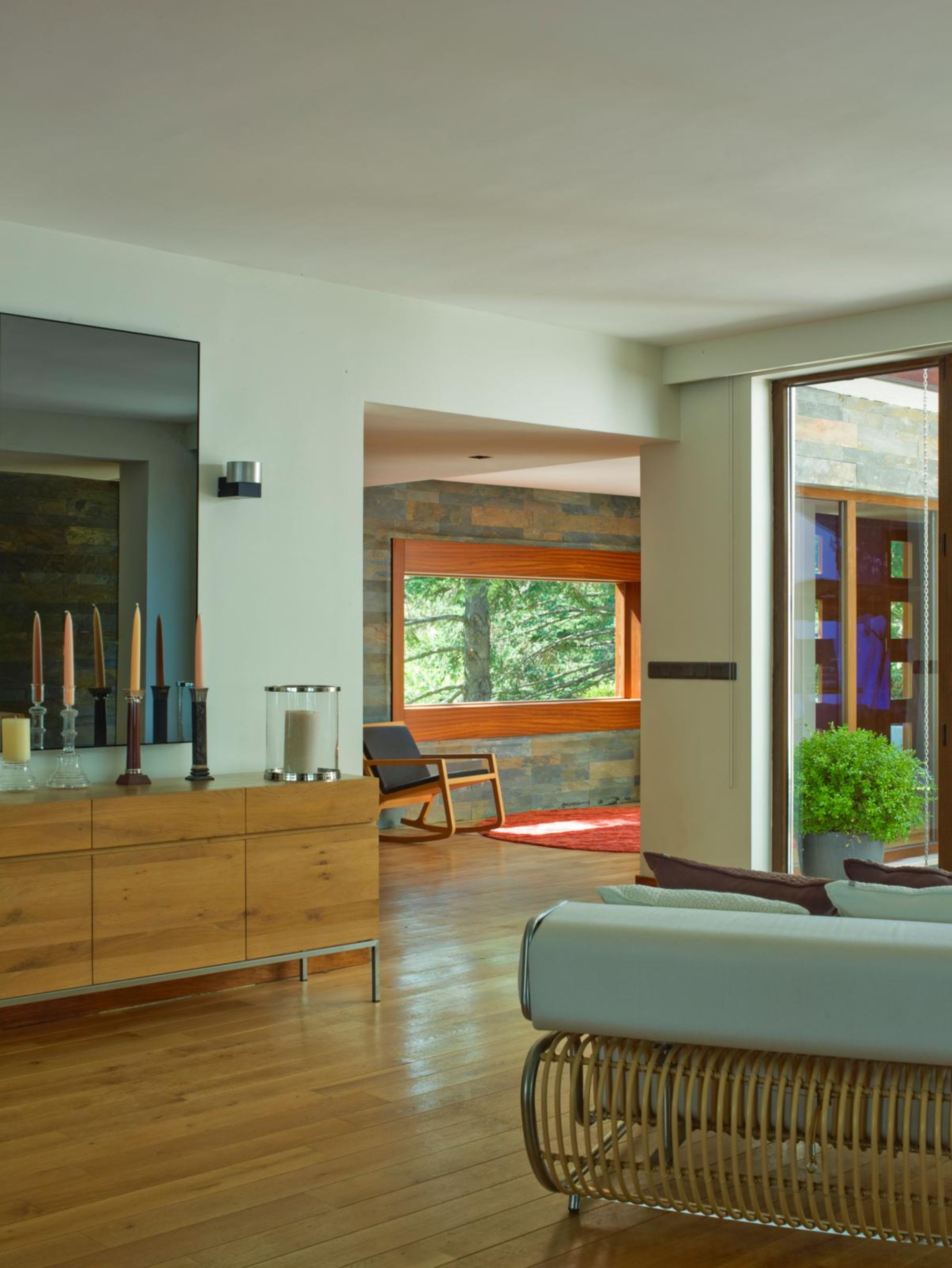 room with wood floors, white walls, and multiple candles on a credenza