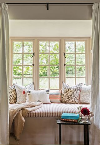 window seat with striped seat cover and cushions with leafy view behind