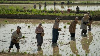 A group of workers sow seeds in a paddy field in the second season of Apple TV Plus series Pachinko