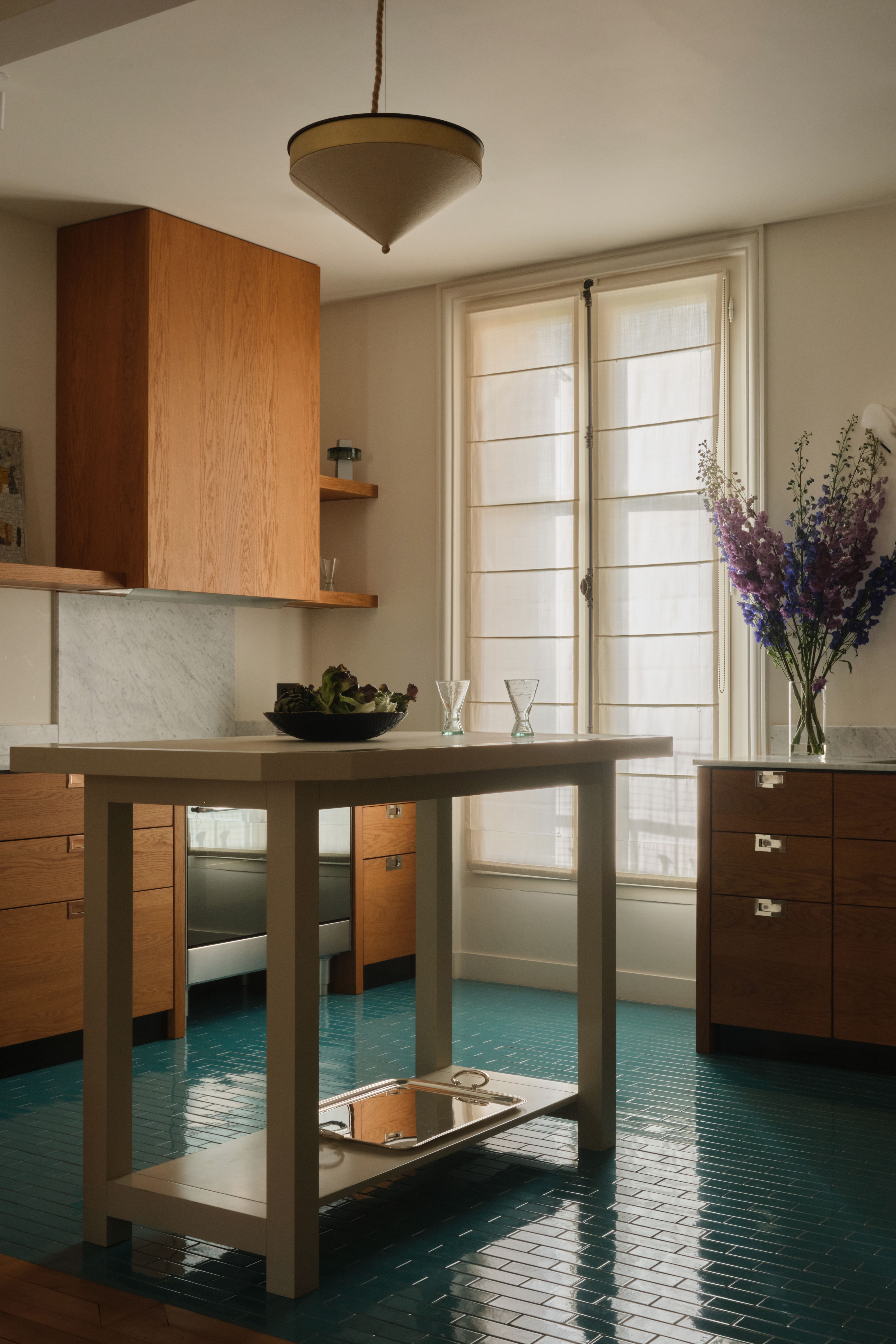 A colorful kitchen pairing wood, marble, and sleek chrome with a glazed ceramic floor of blue tiles.