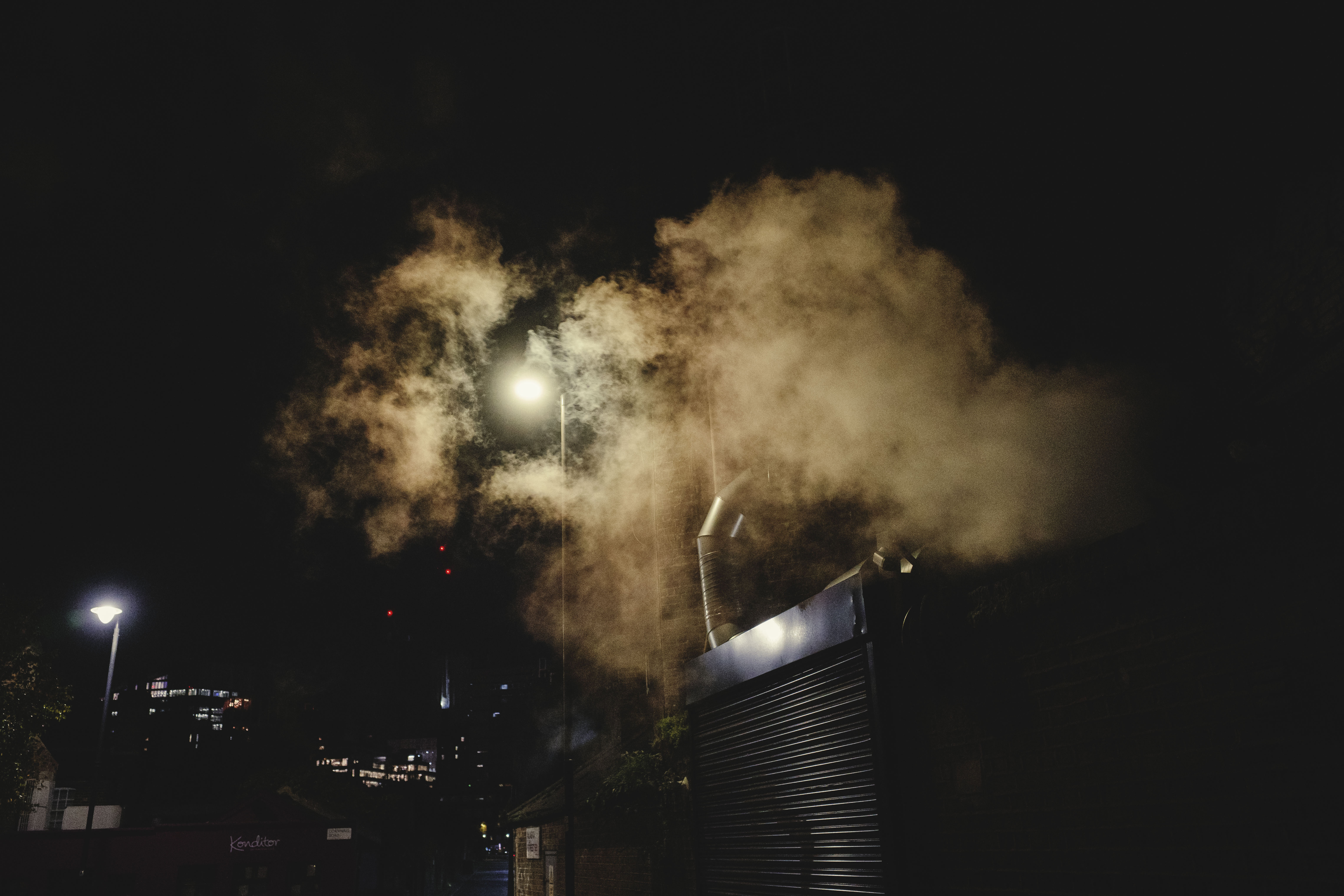 Ricoh GR IV sample images - backlit smoke exiting a ventilation pipe on a London street at night