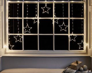 A warm white micro LED star curtain light on cream framed window