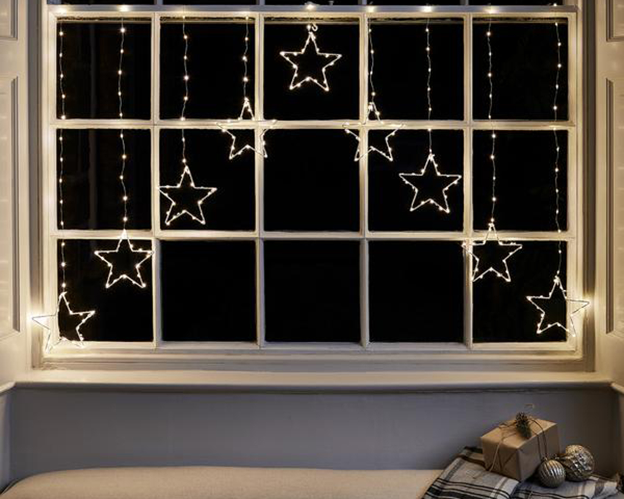 A warm white micro LED star curtain light on cream framed window