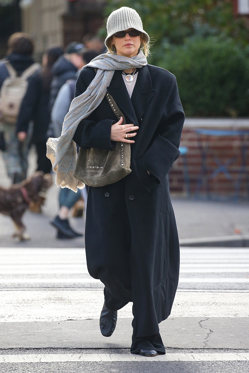 Jennifer Lawrence wearing a knit beanie, oversized coat, scarf, flats, and suede studded bag in NYC