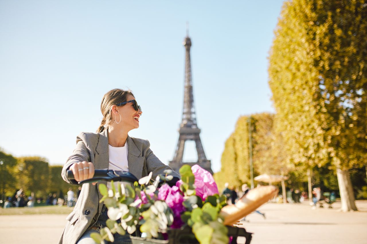 Tourist riding bicycle smiling at park in Paris, one of the world&#039;s most popular cities