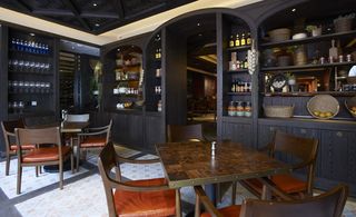 Catalunya, Hong Kong, China. A restaurant with tables and chairs, wooden wall shelves and patterned floor tiles.