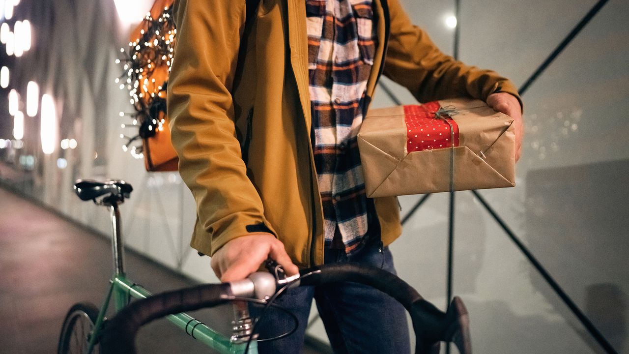 cyclists walking with his bike folding a neatly wrapped christmas present