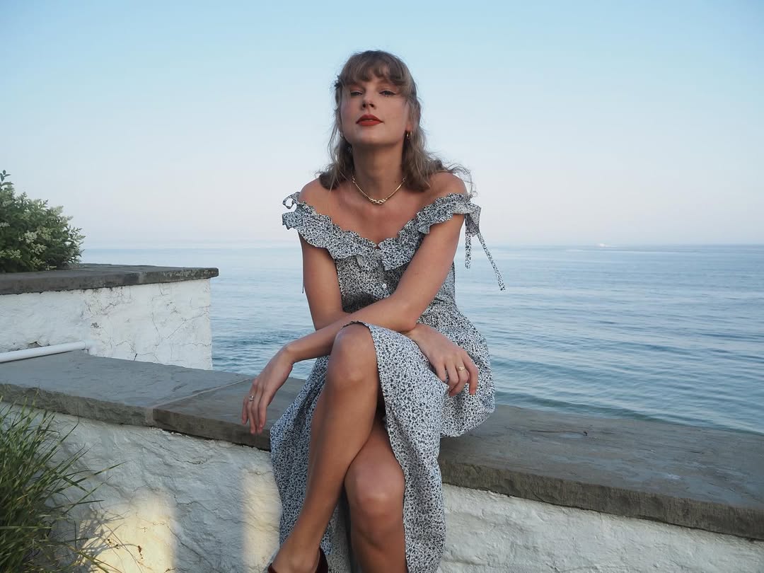 Taylor Swift on her home's balcony wearing a doen dress