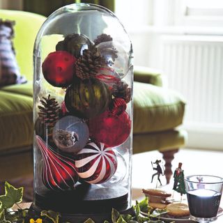 A living room with a Christmas ball display under a glass dome