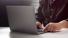 A stock image of a man sitting at a table using a computer.