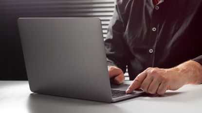 A stock image of a man sitting at a table using a computer.
