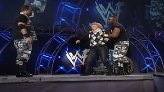 The Dudley Boyz prepare to powerbomb Mae Young off the stage