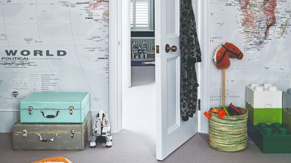 A playroom with a world map wallpaper, Lego storage and toy storage basket and vintage suitcases