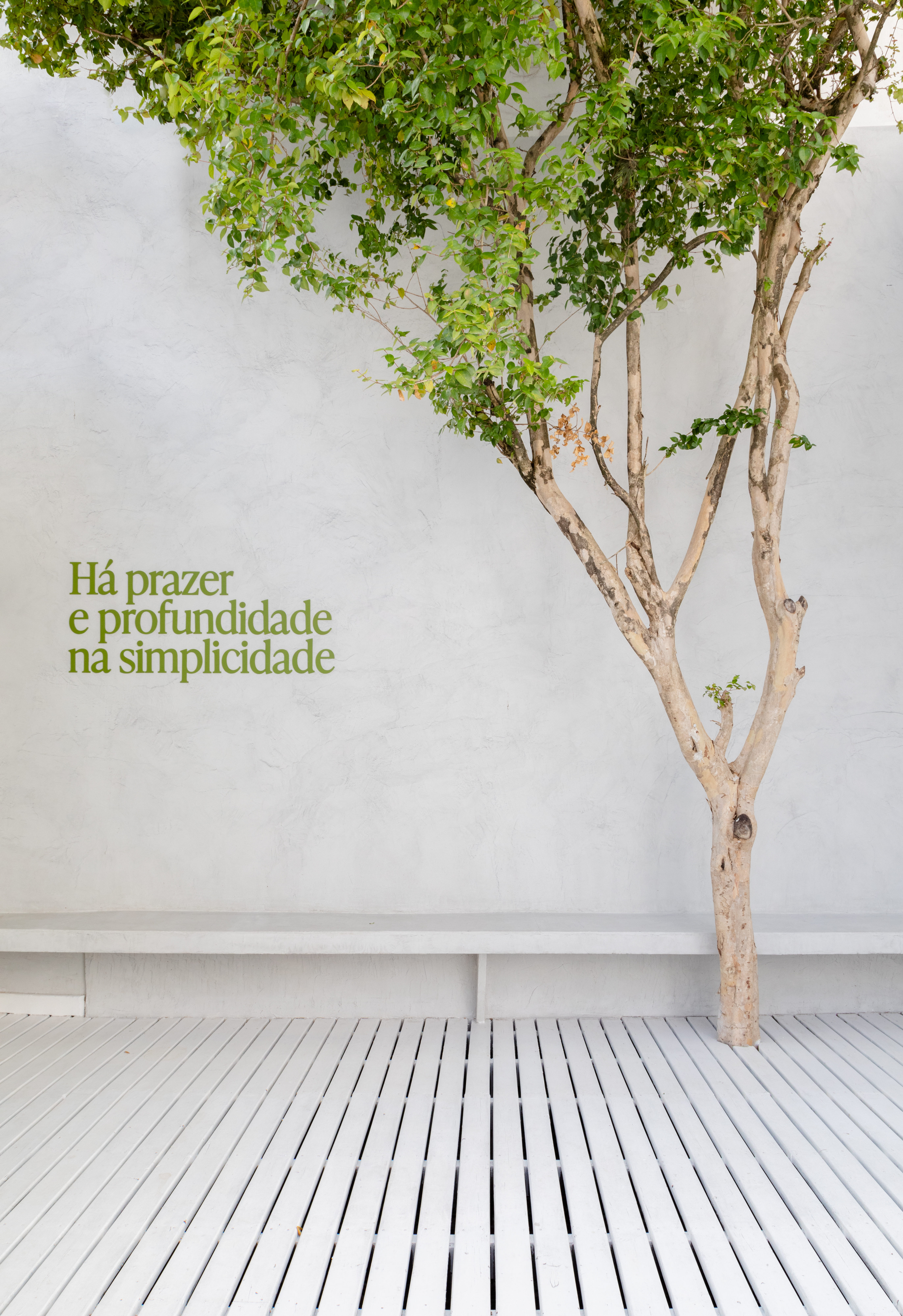 A white-washed, plastered matcha cafe with sculptural decor features monochromatic furnishings and an emerald green and chrome bar counter.