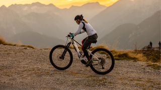 Woman on mountain bike climbing up a rocky path